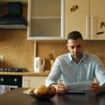 Hombre revisando documentos en la mesa de la cocina